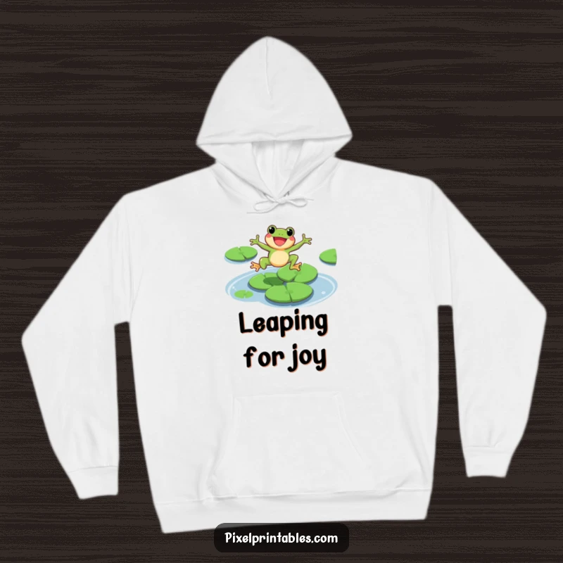 Funny pixel frog character leaping exuberantly over lily pads, cozy hoodie design, retro gamer style.